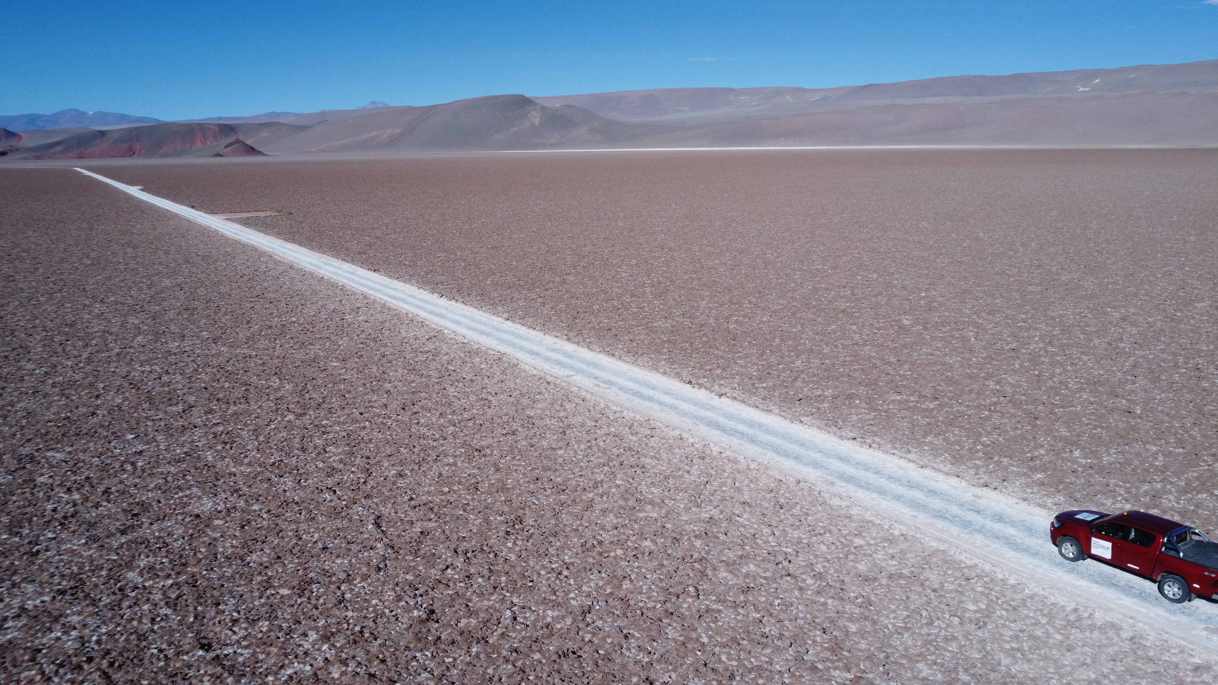 Vista aérea de salar de litio en la Puna argentina con vehículo de exploración